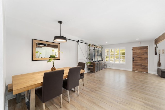 dining room featuring a barn door, baseboards, light wood-style flooring, and recessed lighting