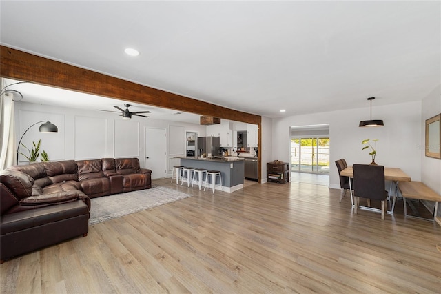 living room with light wood-type flooring, beam ceiling, and recessed lighting