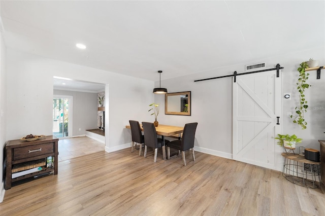 dining area with light wood finished floors, a barn door, and baseboards