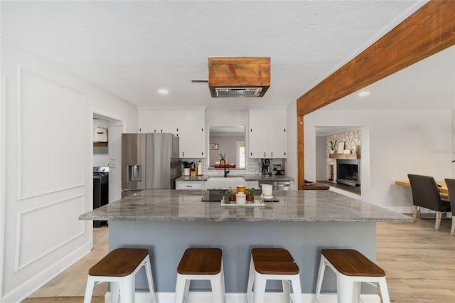 kitchen featuring tasteful backsplash, white cabinetry, appliances with stainless steel finishes, and a kitchen breakfast bar