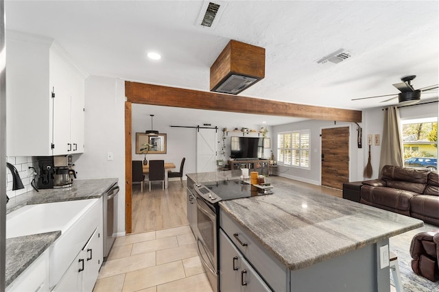 kitchen featuring stainless steel appliances, visible vents, a barn door, open floor plan, and a kitchen island