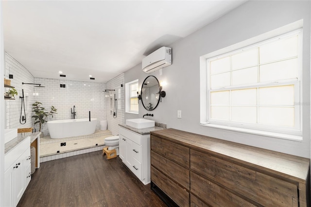 bathroom featuring wood finished floors, vanity, a freestanding bath, an AC wall unit, and tiled shower