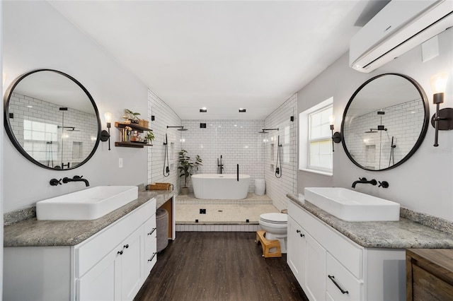 full bathroom with wood finished floors, a freestanding tub, a wall mounted air conditioner, and a sink