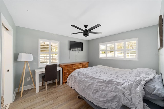 bedroom with a ceiling fan, multiple windows, baseboards, and wood finished floors