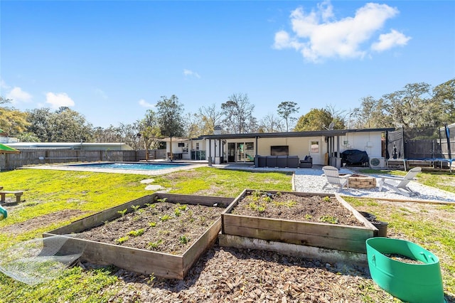 rear view of house featuring a trampoline, a fenced in pool, a garden, and a fenced backyard