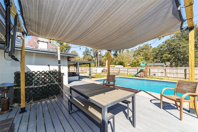 wooden deck with a fenced in pool, a fenced backyard, and a playground