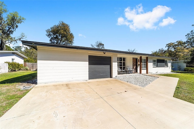 ranch-style house featuring a garage, fence, a front lawn, and concrete driveway