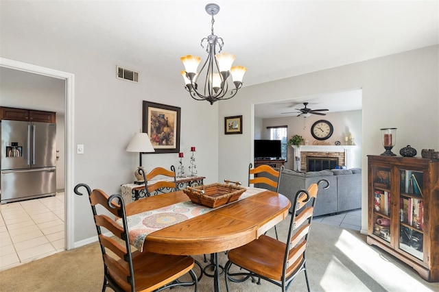 dining area featuring a brick fireplace, visible vents, light carpet, and light tile patterned floors