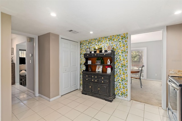 interior space with visible vents, stainless steel electric range oven, baseboards, and wallpapered walls