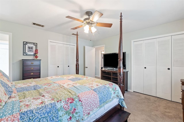 bedroom with light carpet, a ceiling fan, visible vents, and multiple closets