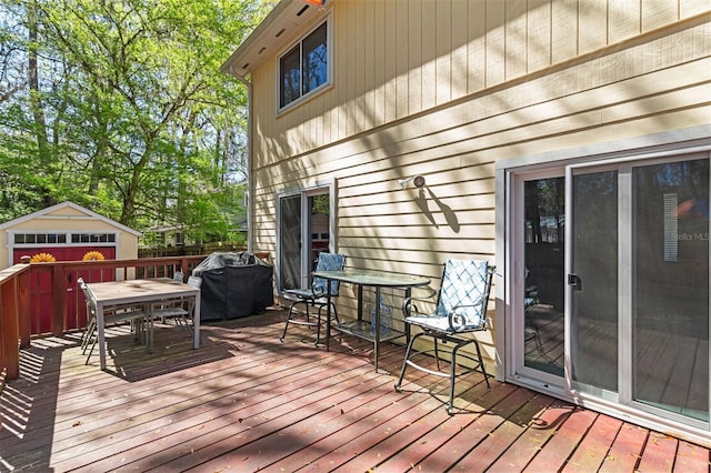 wooden terrace featuring area for grilling, a shed, outdoor dining space, and an outdoor structure