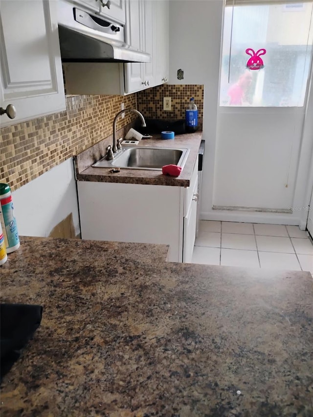 kitchen with dark stone countertops, light tile patterned floors, a sink, decorative backsplash, and white cabinetry