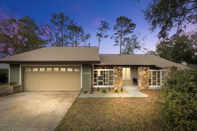 view of front of house featuring a garage, concrete driveway, roof with shingles, and stone siding