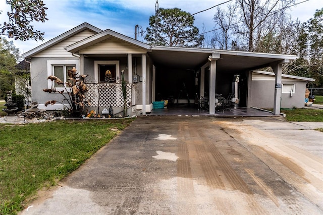 view of front of home with driveway, a carport, a front yard, and stucco siding