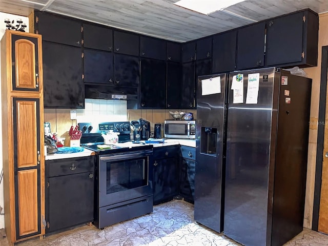 kitchen featuring dark cabinets, stainless steel appliances, light countertops, under cabinet range hood, and backsplash