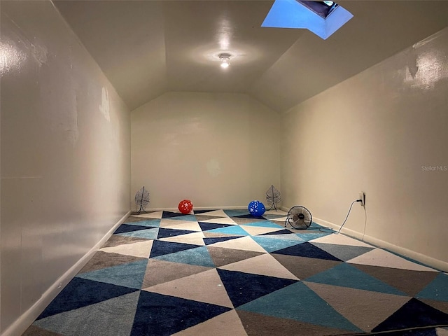 interior space featuring vaulted ceiling with skylight and baseboards