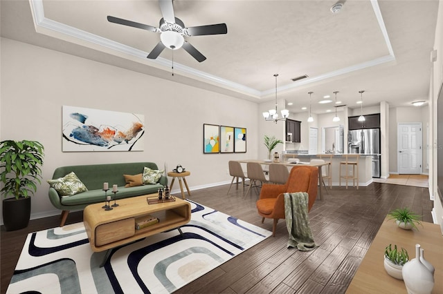 living room with a tray ceiling, dark wood-style flooring, and ornamental molding