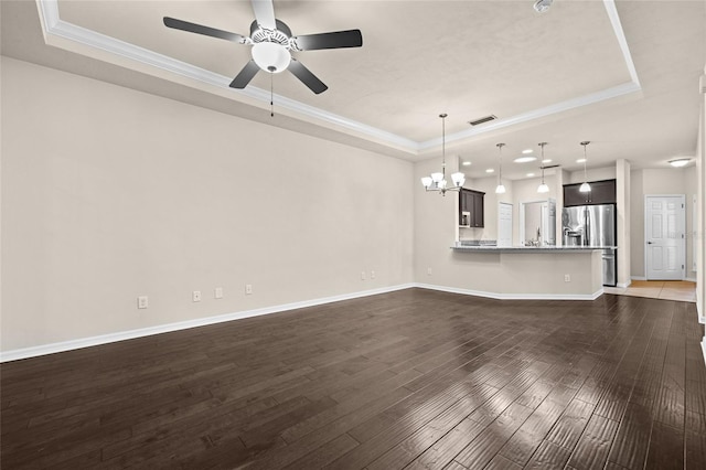 unfurnished living room with dark wood finished floors, a raised ceiling, ornamental molding, baseboards, and ceiling fan with notable chandelier