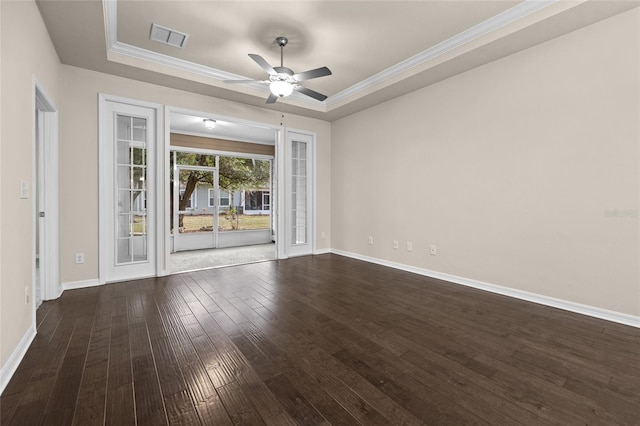 unfurnished room with baseboards, a raised ceiling, dark wood finished floors, and ornamental molding