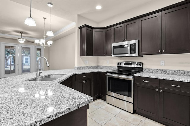 kitchen with light stone counters, pendant lighting, stainless steel appliances, ornamental molding, and a sink