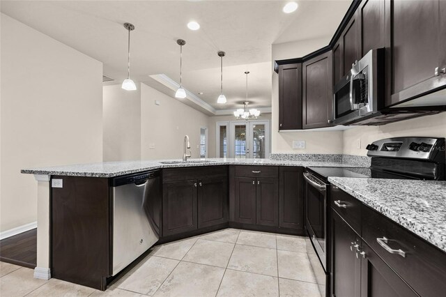 kitchen with a raised ceiling, appliances with stainless steel finishes, a sink, and light stone counters