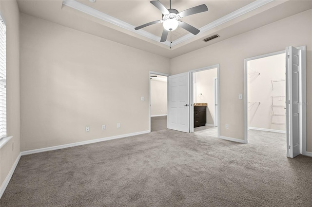 unfurnished bedroom with carpet, visible vents, a raised ceiling, and ornamental molding