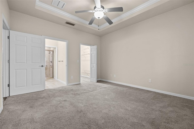 unfurnished bedroom with ornamental molding, a raised ceiling, visible vents, and light colored carpet