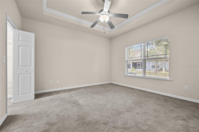 carpeted empty room with baseboards, a raised ceiling, a ceiling fan, and crown molding