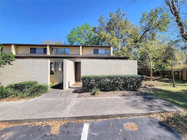 townhome / multi-family property with a front lawn, fence, and stucco siding