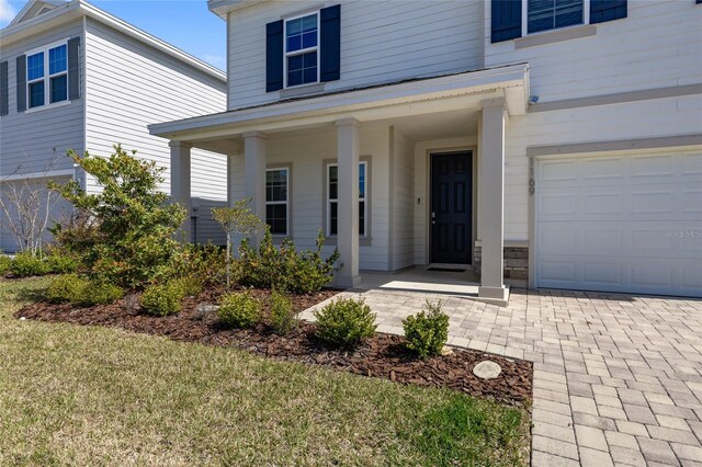 view of exterior entry featuring a garage and a porch