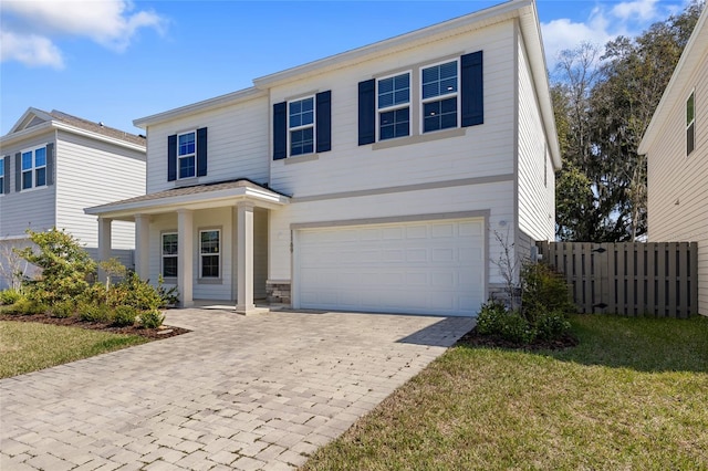 traditional-style home with an attached garage, fence, a front lawn, and decorative driveway