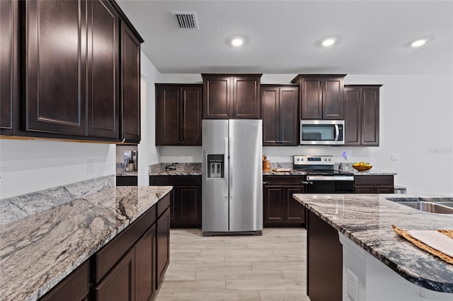 kitchen featuring stainless steel appliances, recessed lighting, stone counters, and visible vents