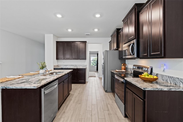 kitchen with appliances with stainless steel finishes, a sink, and dark brown cabinetry