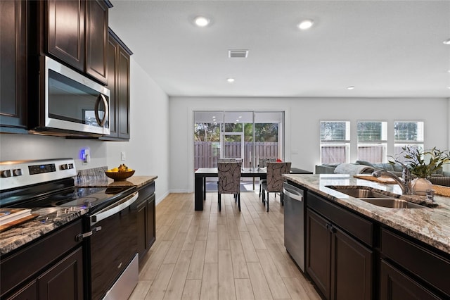 kitchen with light stone counters, light wood finished floors, visible vents, appliances with stainless steel finishes, and a sink