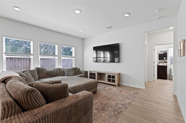 living room featuring light wood-type flooring, baseboards, visible vents, and recessed lighting