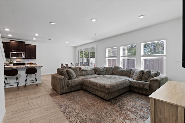 living area with light wood finished floors, visible vents, baseboards, and recessed lighting