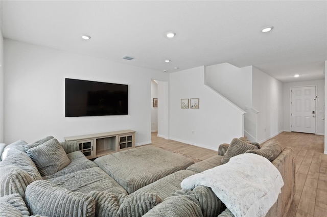 living room featuring baseboards, light wood finished floors, stairs, and recessed lighting