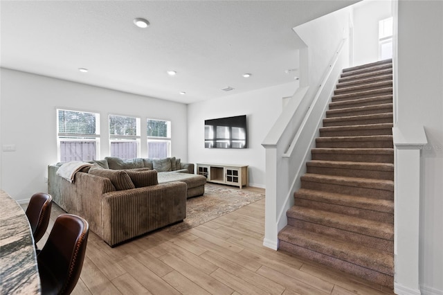 living area featuring light wood-type flooring, baseboards, stairway, and recessed lighting