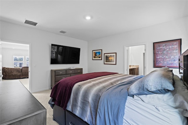 bedroom featuring baseboards, visible vents, ensuite bathroom, and light colored carpet