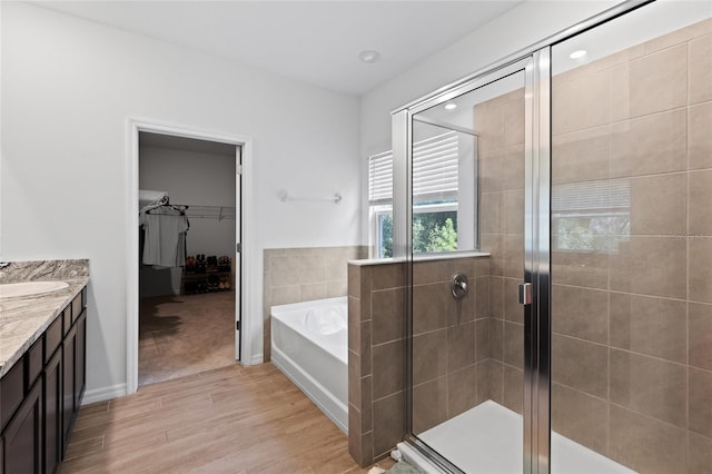 bathroom with wood finished floors, a shower stall, vanity, and a bath