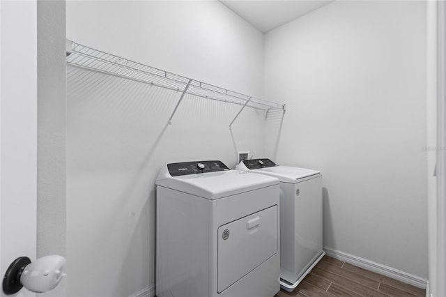 laundry area featuring baseboards, laundry area, washing machine and dryer, and wood tiled floor