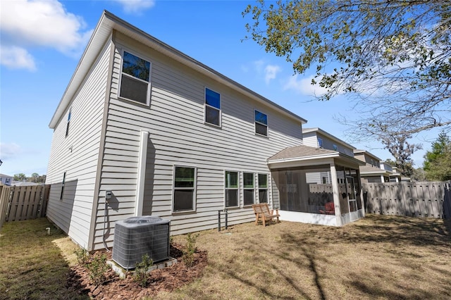 rear view of property with a sunroom, a fenced backyard, a yard, and central air condition unit