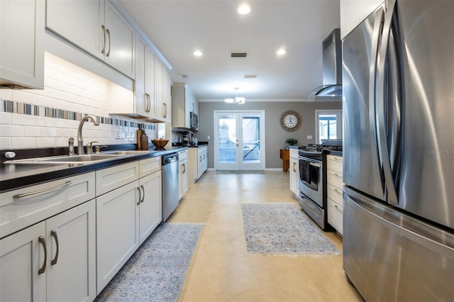 kitchen with stainless steel appliances, a sink, dark countertops, wall chimney range hood, and ornamental molding