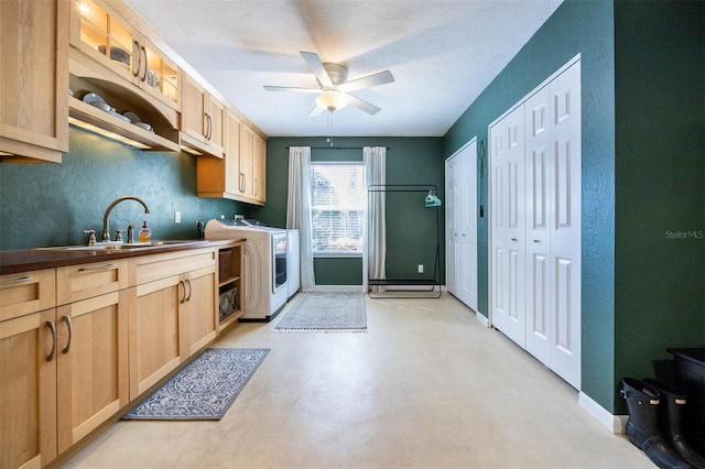 kitchen featuring washing machine and clothes dryer, light brown cabinetry, a ceiling fan, and a sink