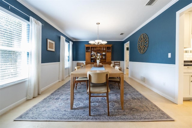 dining space with wainscoting, visible vents, an inviting chandelier, and crown molding