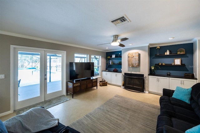 living area with visible vents, crown molding, a ceiling fan, and built in features