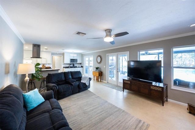 living area featuring baseboards, a ceiling fan, visible vents, and plenty of natural light