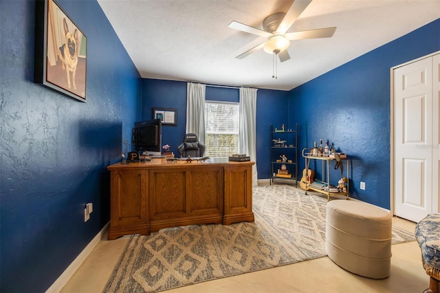 office space with baseboards and ceiling fan
