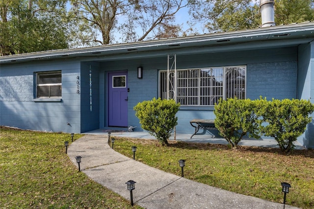 property entrance with concrete block siding and a lawn