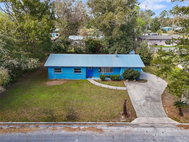 view of front of home featuring metal roof, concrete driveway, and a front yard